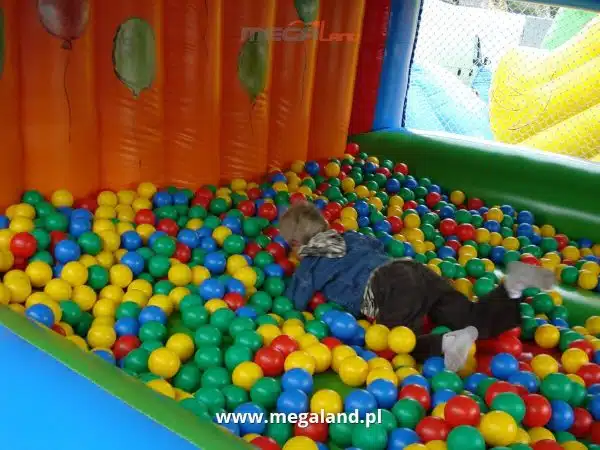 Dziecko bawi się w basenie z kolorowymi piłkami.