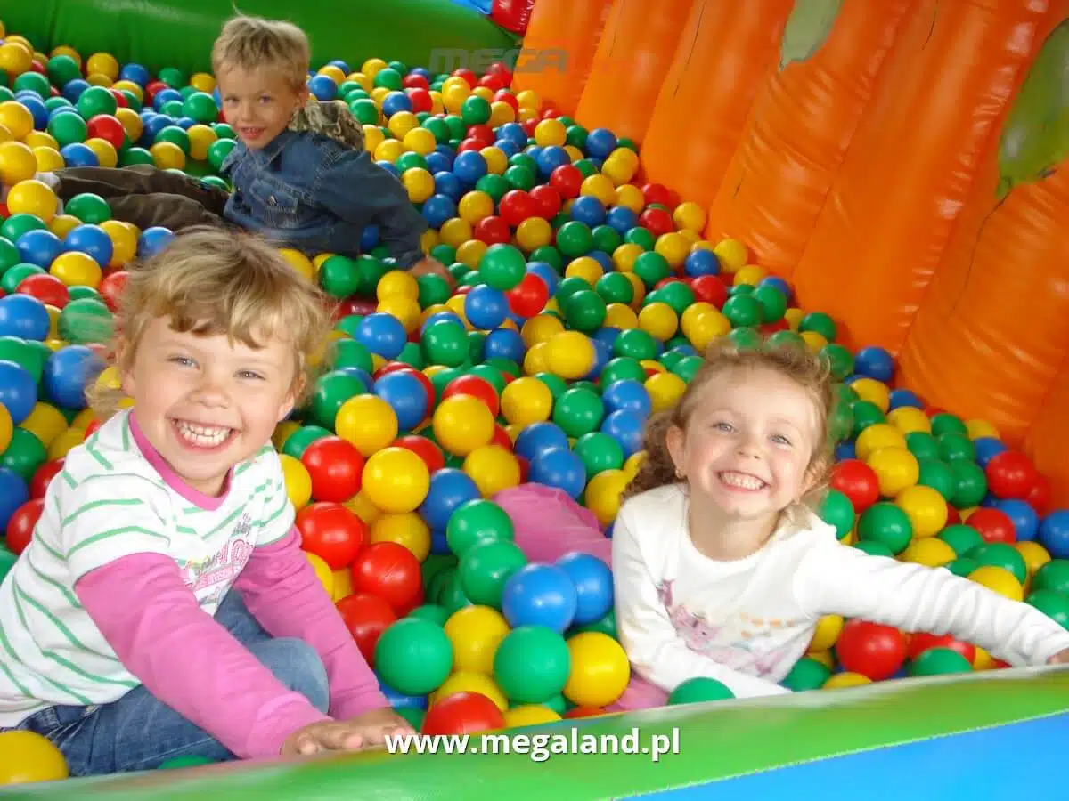 Dzieci bawiące się w basenie z kolorowymi piłkami.