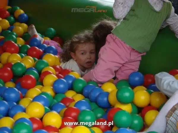 Dziecko bawi się w basenie z kolorowymi piłkami.