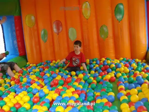 Dzieciaki bawią się w basenie z kolorowymi piłeczkami.