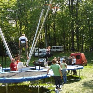 Dzieci bawią się na trampolinach z bungee w parku.