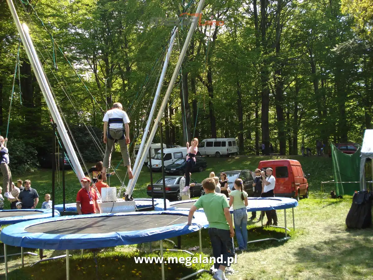 Dzieci bawią się na trampolinach z bungee w parku.