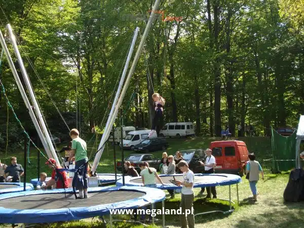 Dzieci bawiące się na trampolinach w parku.