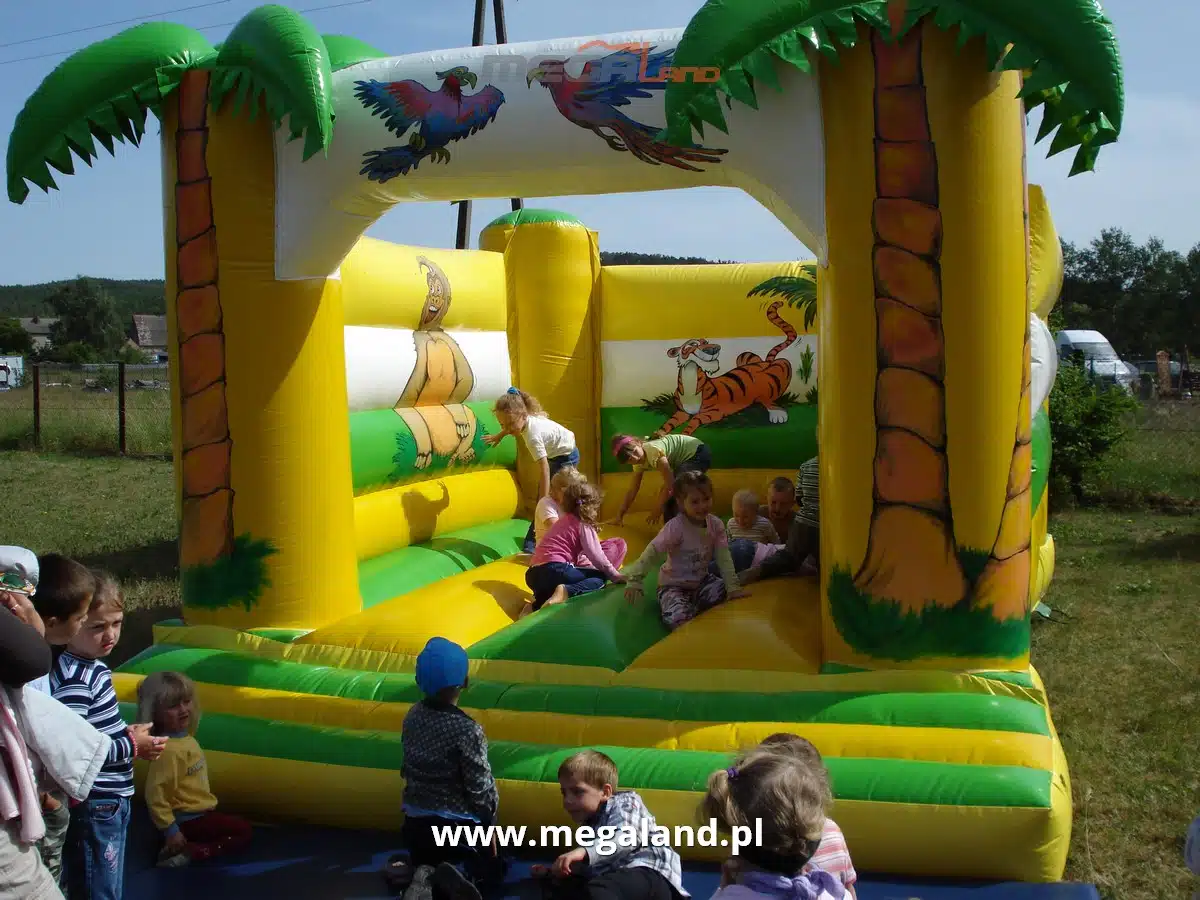 Dzieci bawią się na dmuchanym zamku z motywem dżungli.