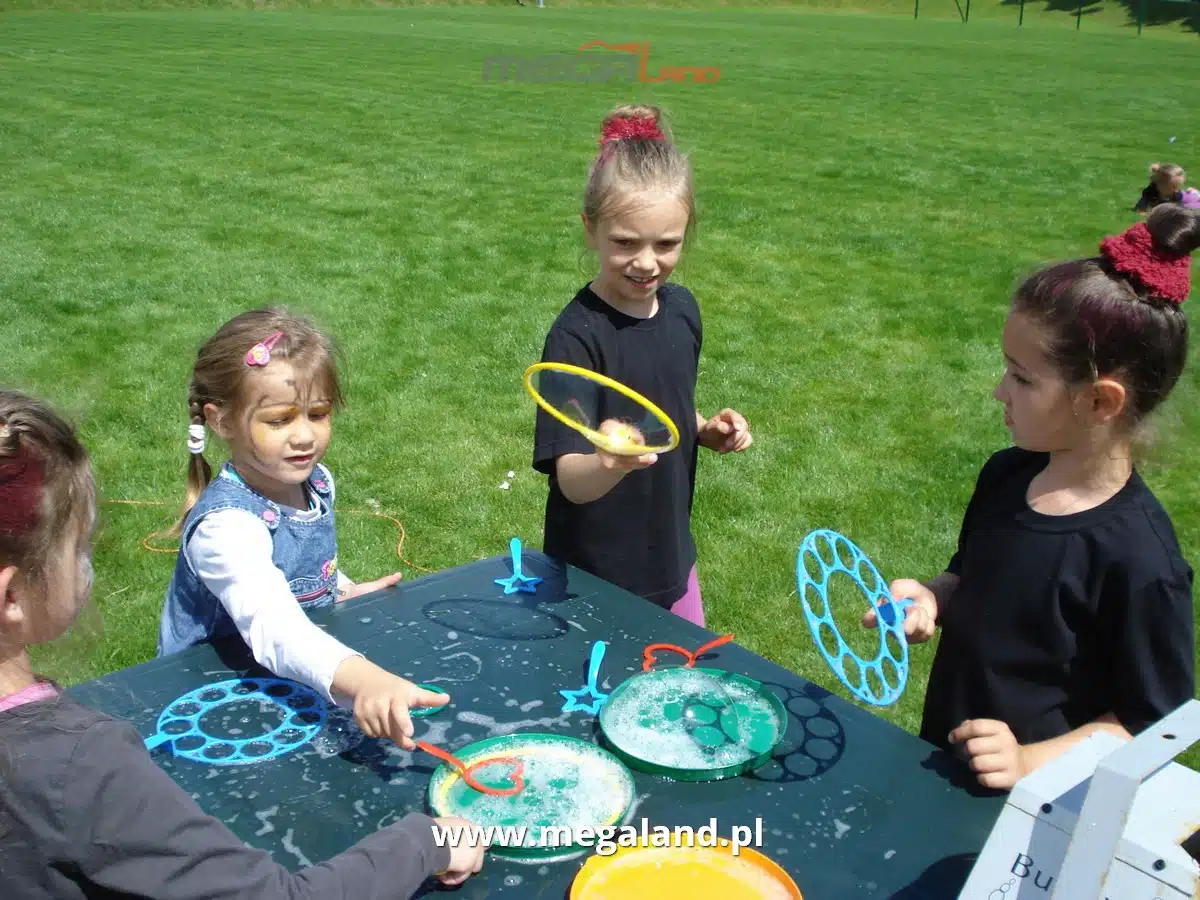 Dzieci bawiące się bańkami mydlanymi na trawie.