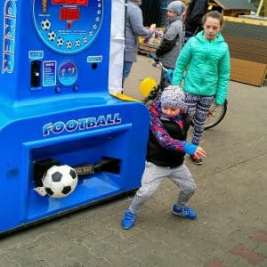 Dziecko gra w automacie piłkarskim na zewnątrz.