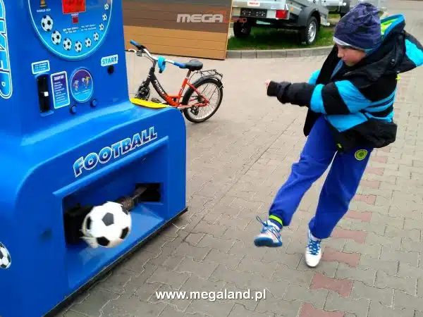 Chłopiec gra w automat do piłki nożnej na zewnątrz.