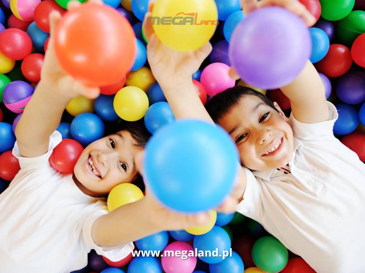 Dzieci bawiące się kolorowymi piłeczkami w sali zabaw.