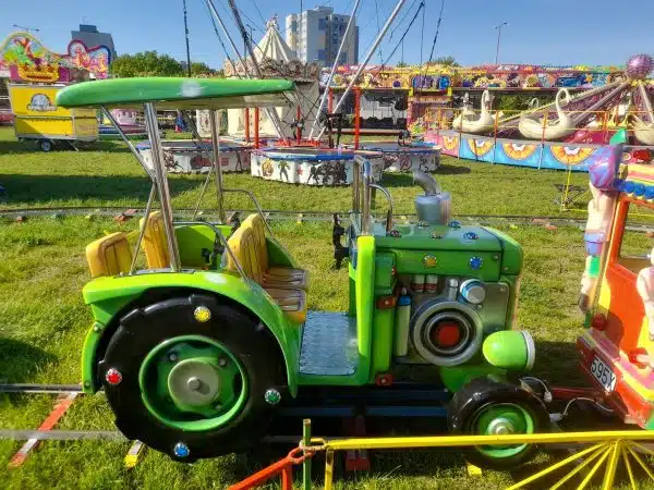 Wagon Kolejki Elektrycznej od Megaland - zielony traktor, który zapewnia dzieciom wrażenia związane z jazdą po farmie, stanowiąc zachętę do odkrywczej zabawy.
